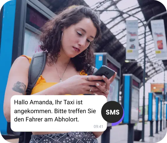 Mädchen mit Rucksack am Bahnhof prüft per SMS die Ankunft ihres Taxis.