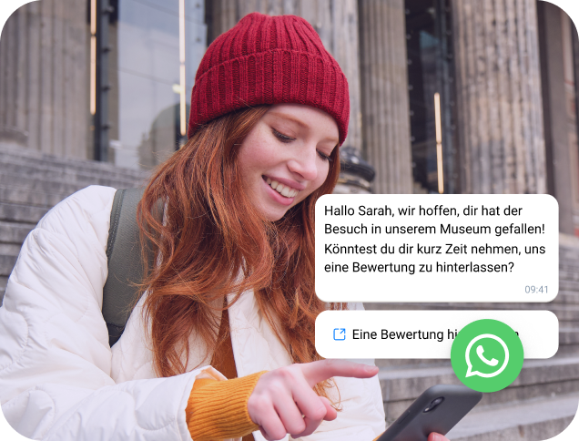 Frau mit roter Mütze prüft eine WhatsApp-Nachricht auf ihrem Handy.
